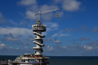 Photo of HAGUE, NETHERLANDS - SEPTEMBER 10, 2022: Scheveningen Pier with Bungy Jump against blue sky on sunny day