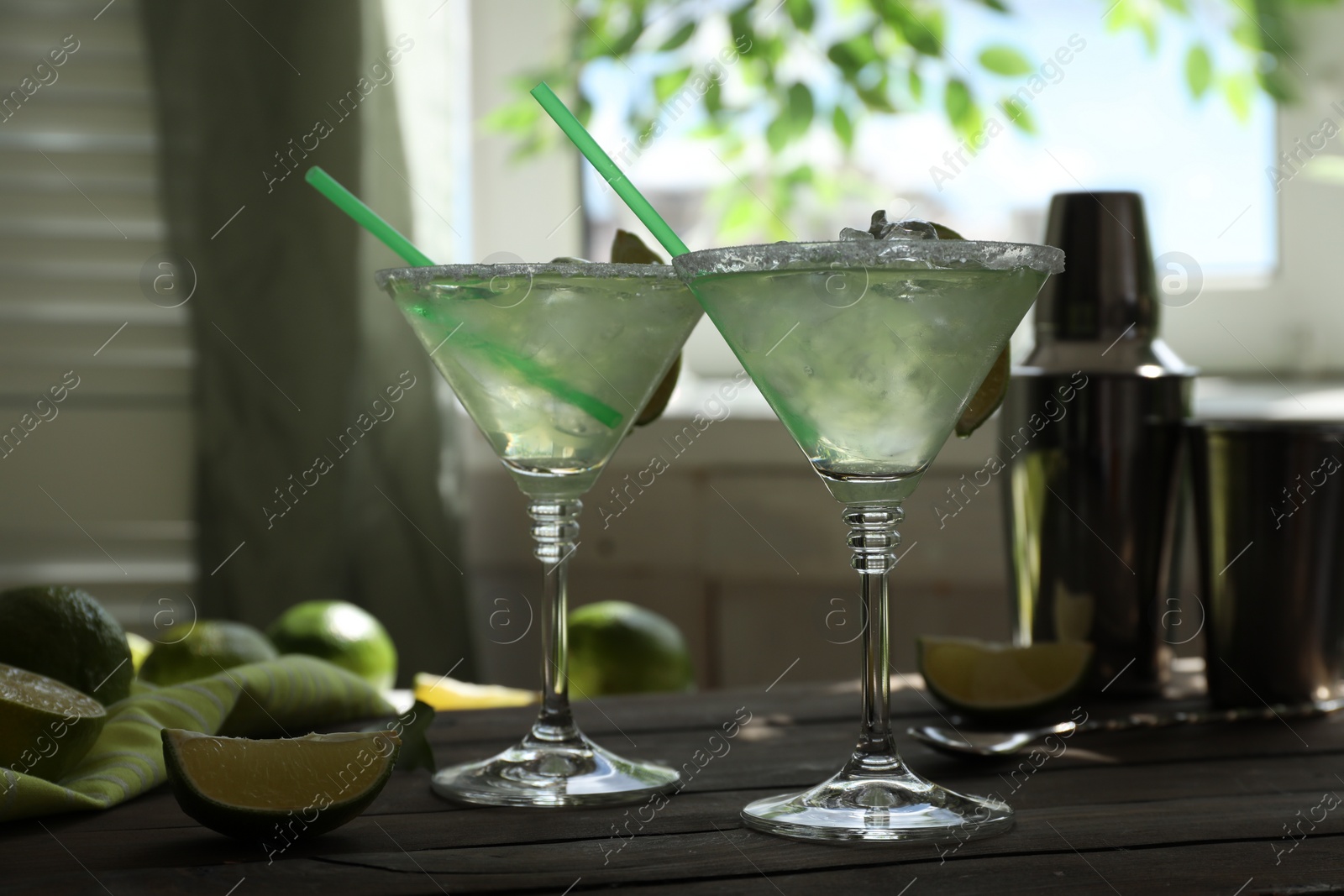 Photo of Delicious Margarita cocktail in glasses and lime on wooden table, closeup