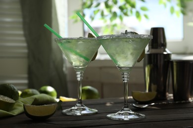 Photo of Delicious Margarita cocktail in glasses and lime on wooden table, closeup