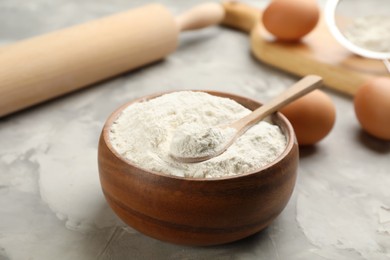 Photo of Bowl of flour with spoon on light grey table