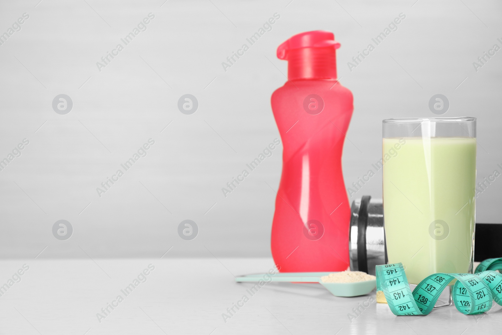 Photo of Tasty shake, bottle, measuring tape and powder on light table, space for text. Weight loss