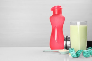 Photo of Tasty shake, bottle, measuring tape and powder on light table, space for text. Weight loss