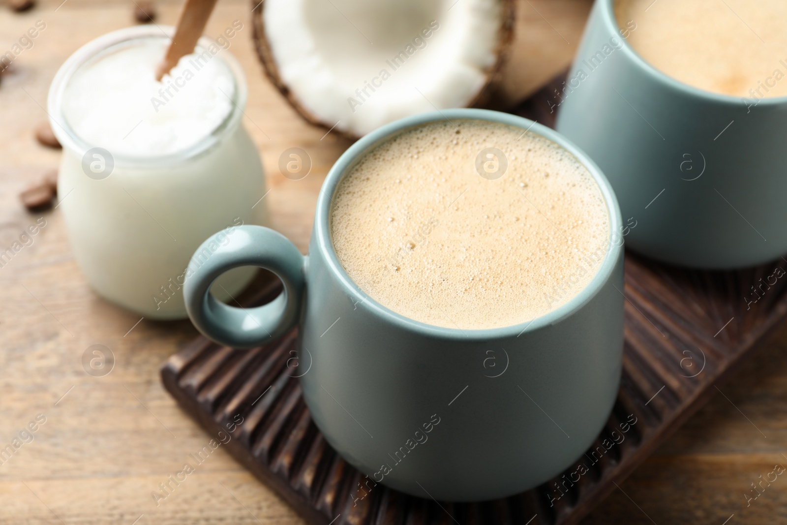 Photo of Delicious coffee with organic coconut oil on wooden table