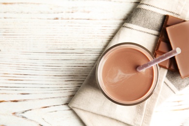 Photo of Flat lay composition with glass of tasty chocolate milk and space for text on wooden background. Dairy drink