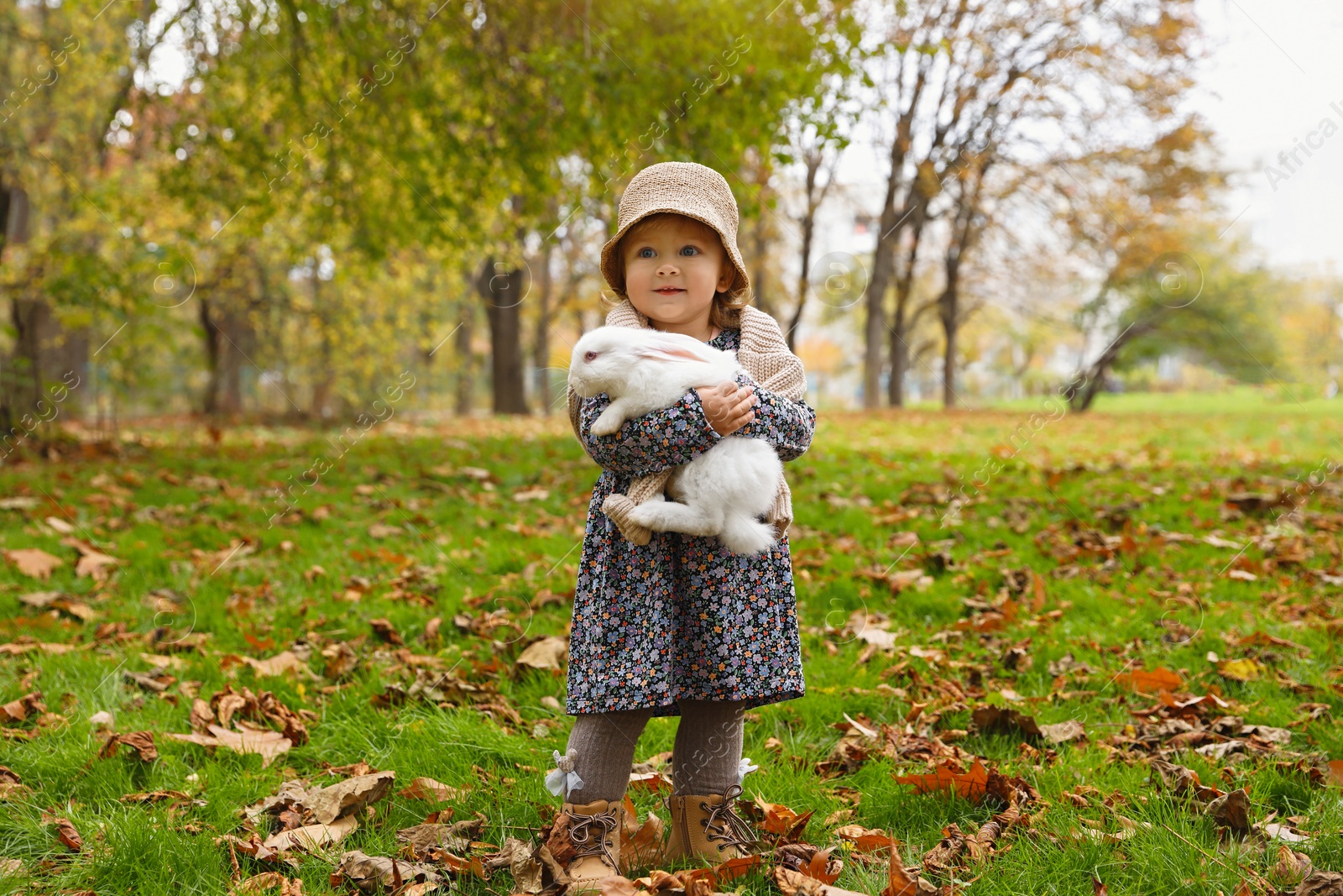 Photo of Girl walking with cute white rabbit in autumn park