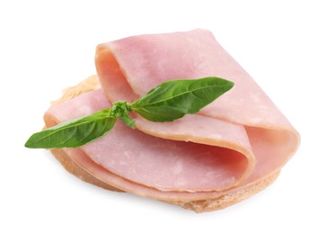 Piece of bread with tasty ham slice and basil isolated on white