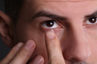 Photo of Closeup view of man putting contact lens in his eye