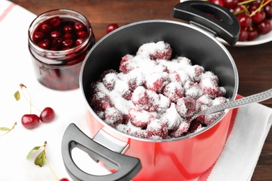 Photo of Pot with cherries and sugar on table, closeup. Making delicious jam
