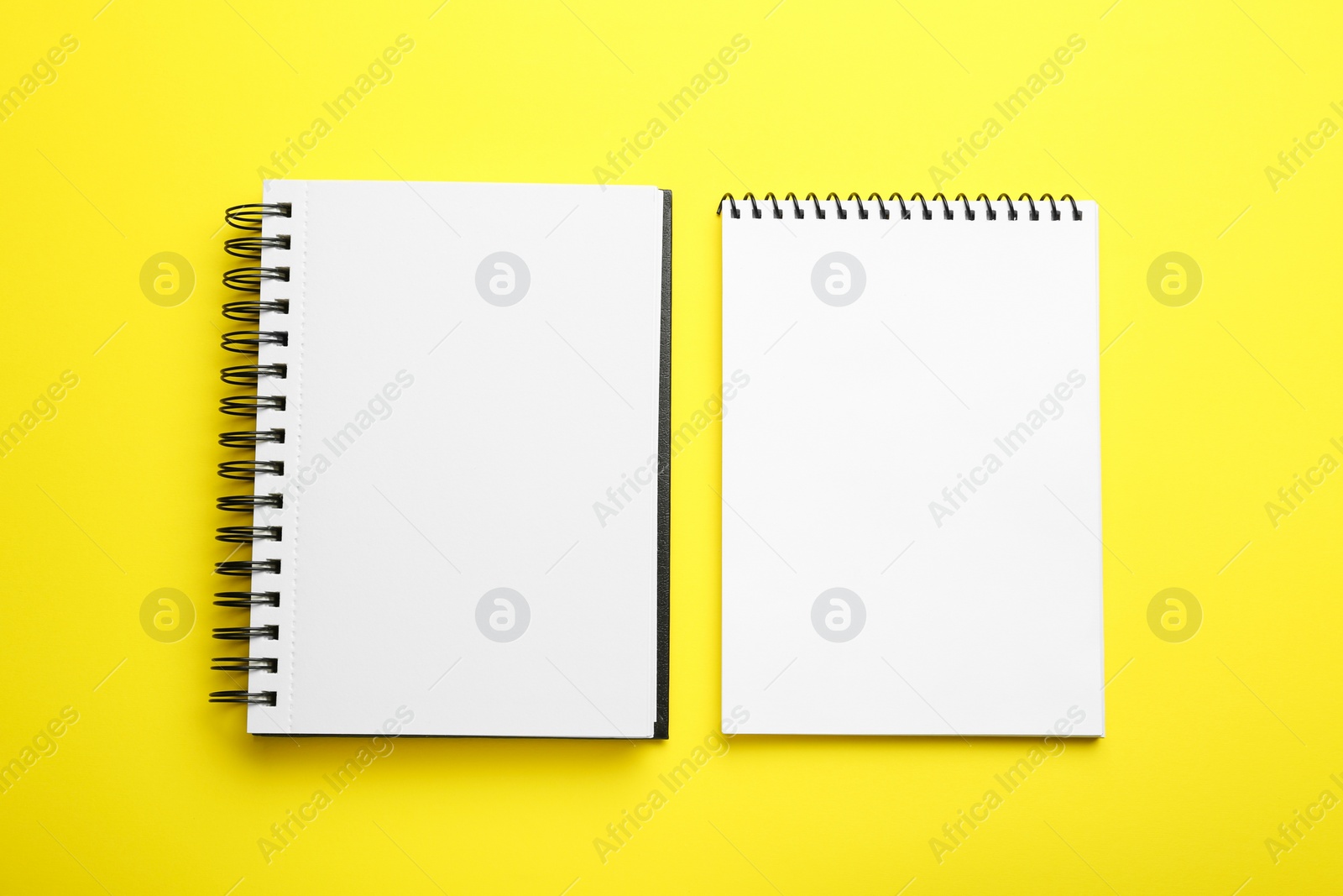 Photo of Notebooks on yellow background, top view. Space for text