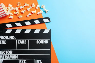 Photo of Clapper board and popcorn on color background, top view with space for text. Visiting cinema