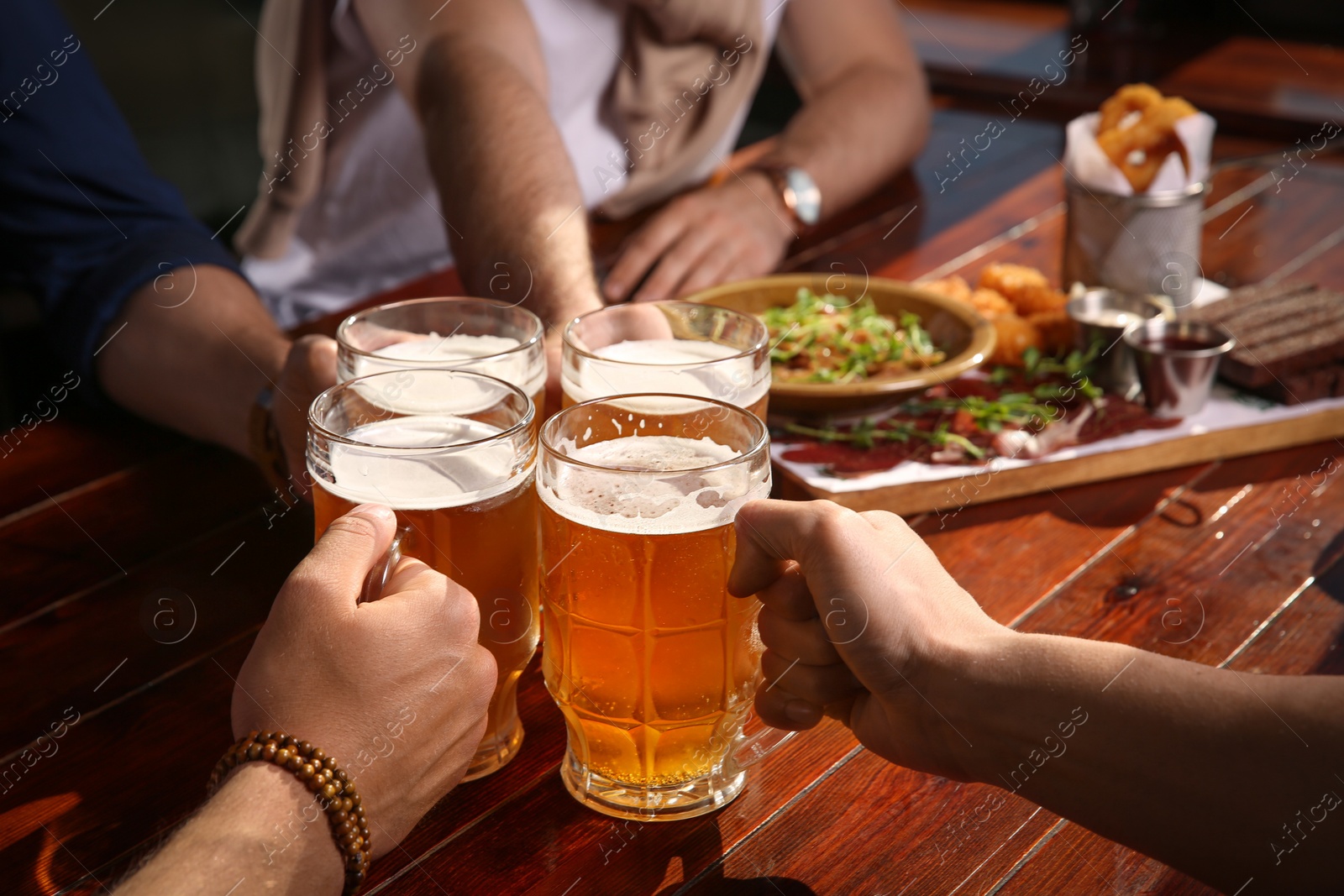 Photo of Friends clinking glasses with beer in pub, closeup