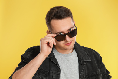 Photo of Young man wearing sunglasses on yellow background