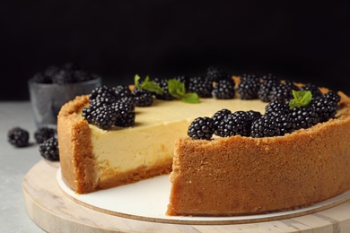 Photo of Delicious cheesecake decorated with blackberries on table