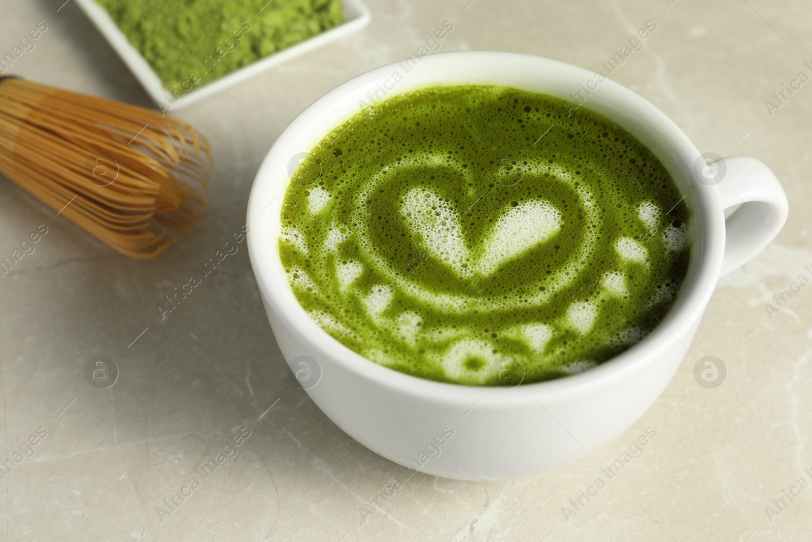 Photo of Delicious matcha latte in cup on marble table, closeup