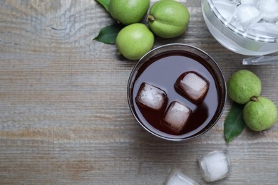 Photo of Delicious liqueur with ice and green walnuts on wooden table, flat lay. Space for text