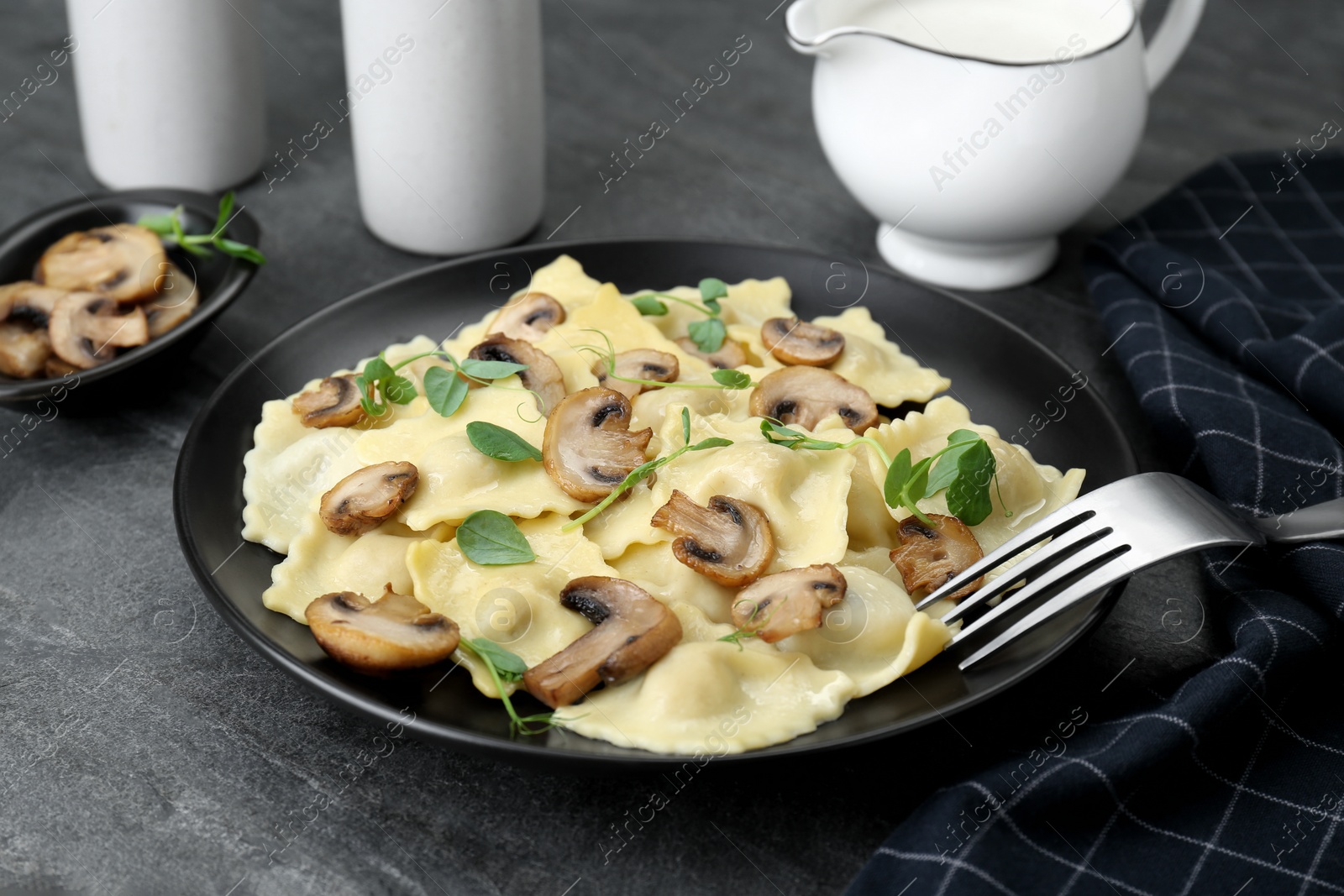 Photo of Delicious ravioli with mushrooms served on grey table, closeup