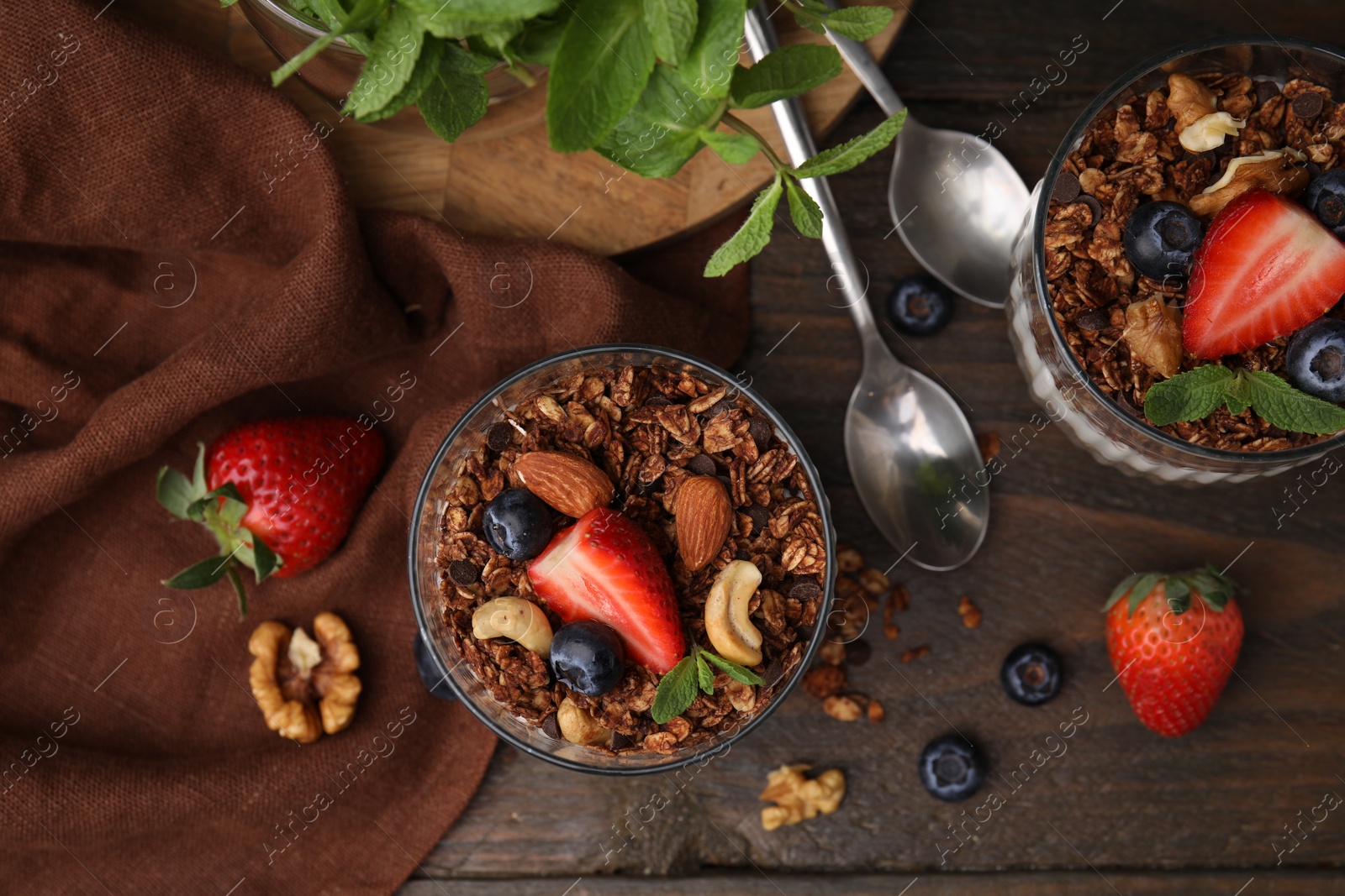 Photo of Tasty granola, berries, nuts and mint on wooden table, flat lay