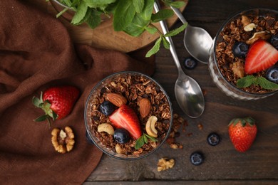 Photo of Tasty granola, berries, nuts and mint on wooden table, flat lay