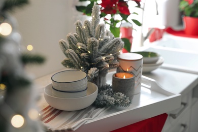 Photo of Tray with little Christmas tree, candle and dishware on kitchen counter
