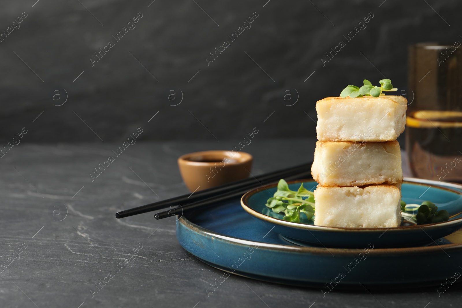 Photo of Delicious turnip cake with microgreens served on black table. Space for text