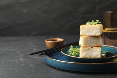 Photo of Delicious turnip cake with microgreens served on black table. Space for text