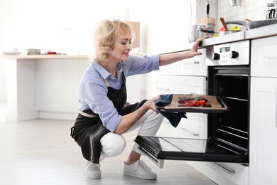 Professional chef putting meat into oven in kitchen