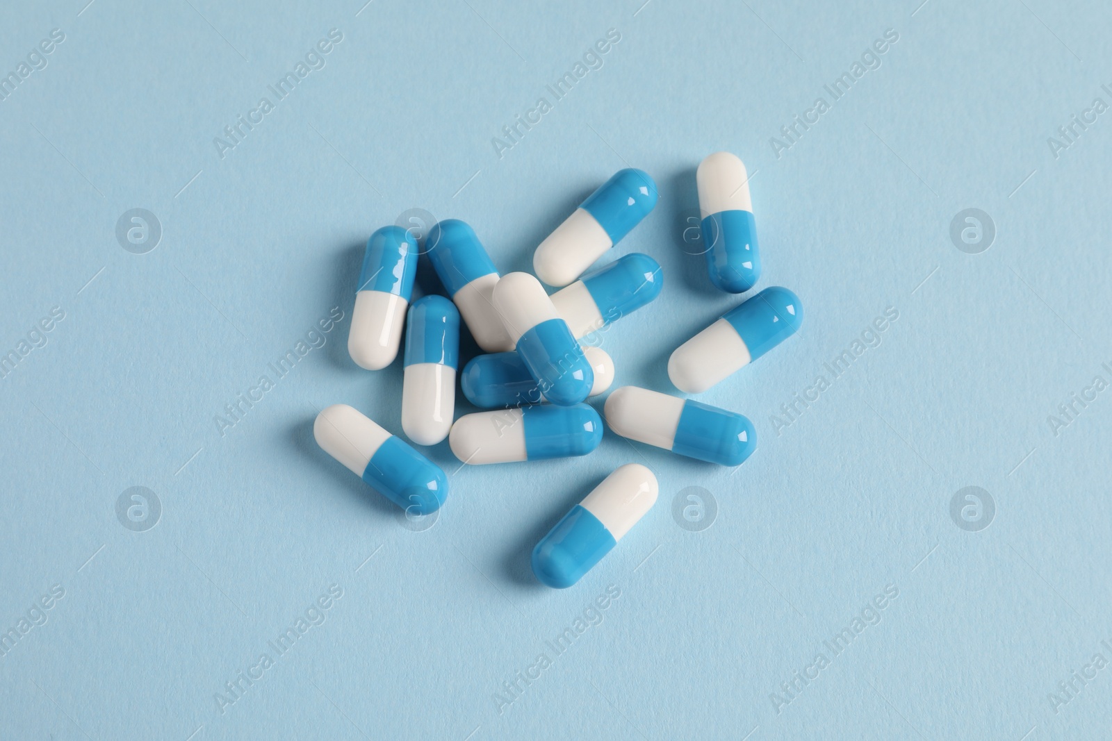 Photo of Pile of pills on light blue background, flat lay