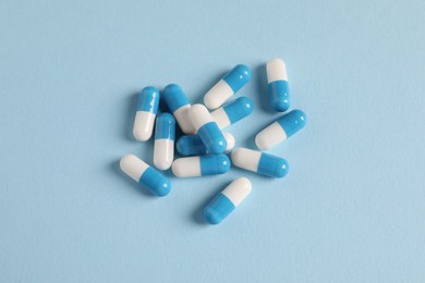 Pile of pills on light blue background, flat lay