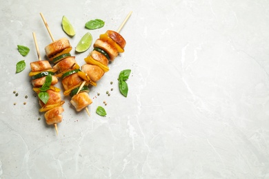 Photo of Delicious chicken shish kebabs with vegetables on grey marble table, flat lay. Space for text