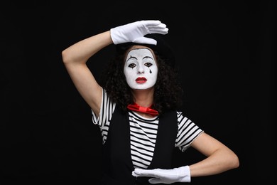 Young woman in mime costume posing on black background