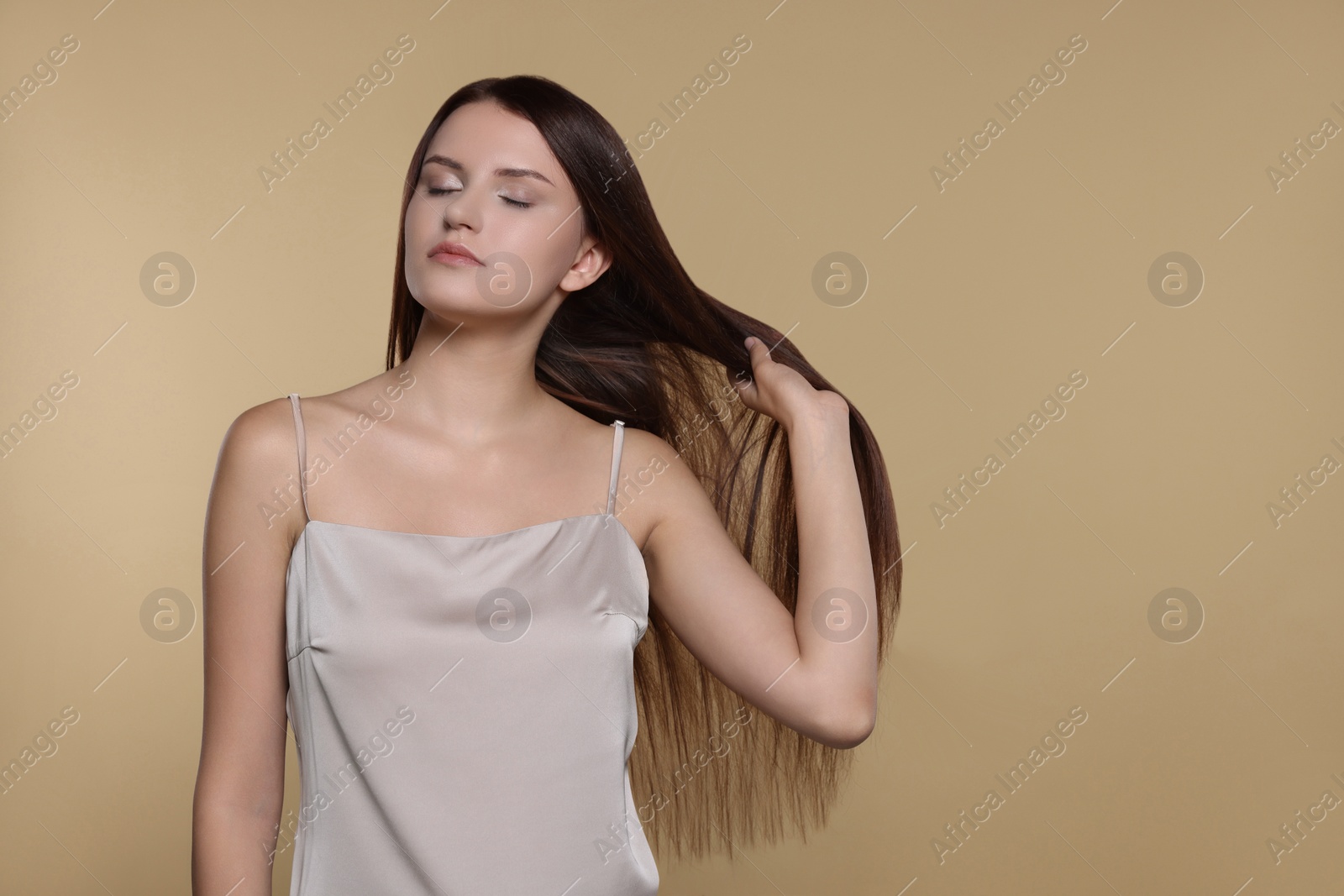 Photo of Portrait of beautiful young woman with healthy strong hair on beige background