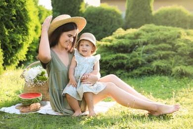 Photo of Mother with her baby daughter having picnic in garden on sunny day