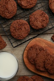 Delicious chocolate chip cookies and glass of milk on wooden table, flat lay