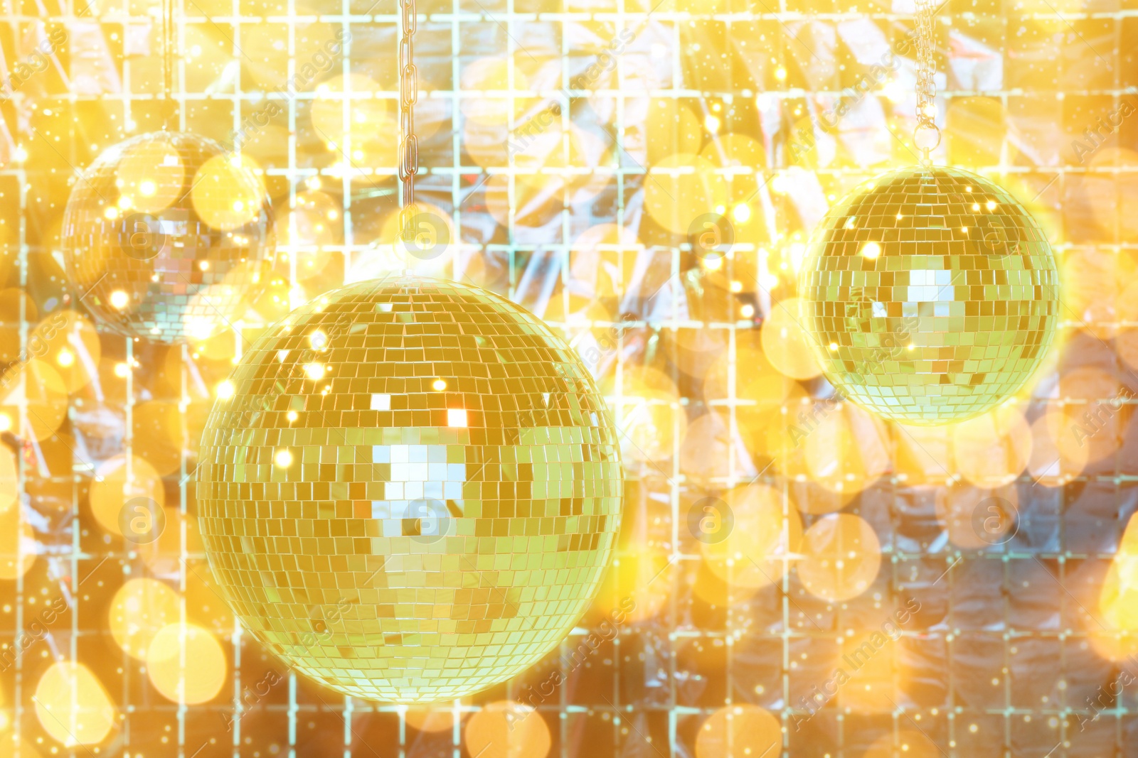 Image of Shiny disco balls against foil party curtain under golden lights, bokeh effect