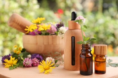 Bottles of essential oil and flowers on wooden table