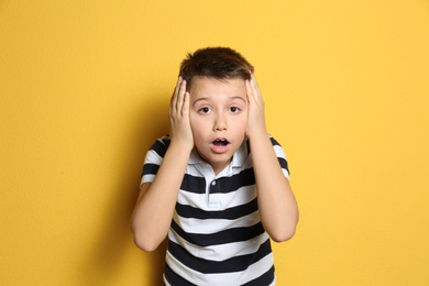 Portrait of emotional preteen boy on yellow background