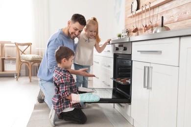 Photo of Father with his kids baking cookies in oven at home