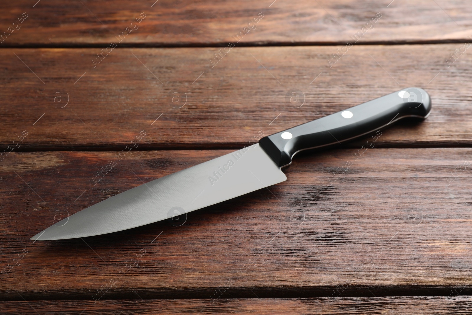 Photo of One sharp knife on wooden table, closeup