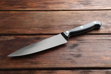 Photo of One sharp knife on wooden table, closeup