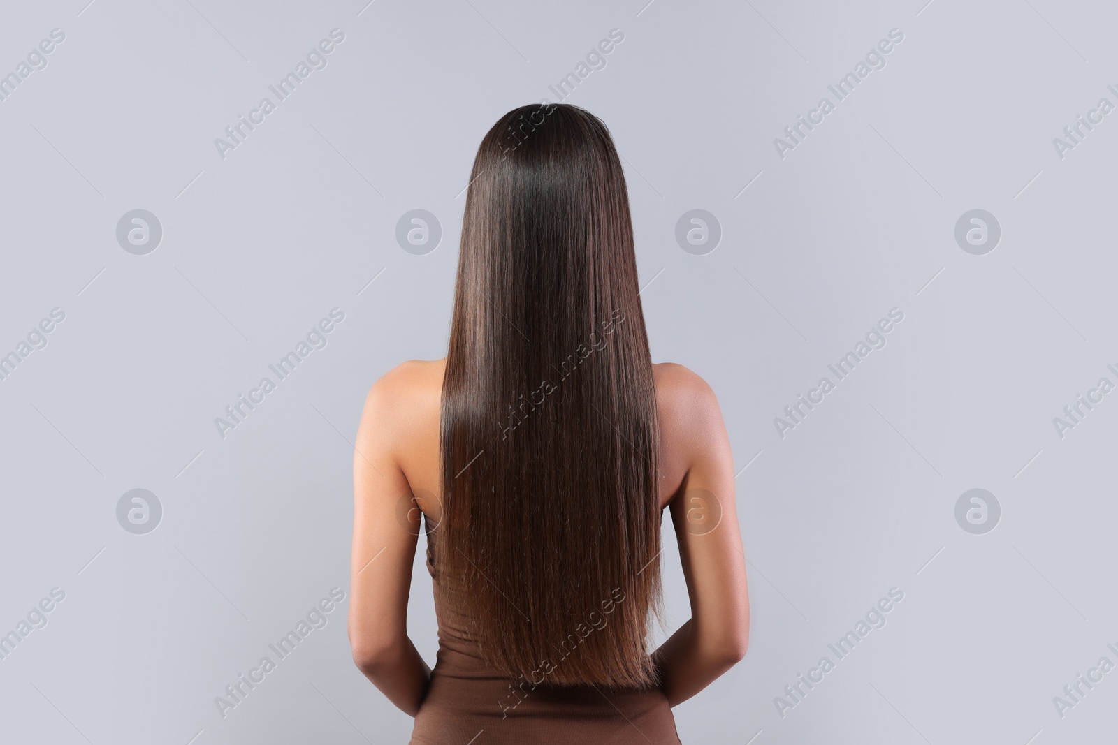 Photo of Hair styling. Woman with straight long hair on grey background, back view