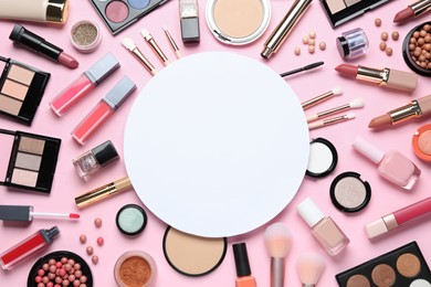 Flat lay composition with makeup products and blank round card on pink background, space for text