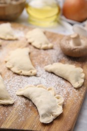 Photo of Raw dumplings (varenyky) with tasty filling on wooden board, closeup. Traditional Ukrainian dish