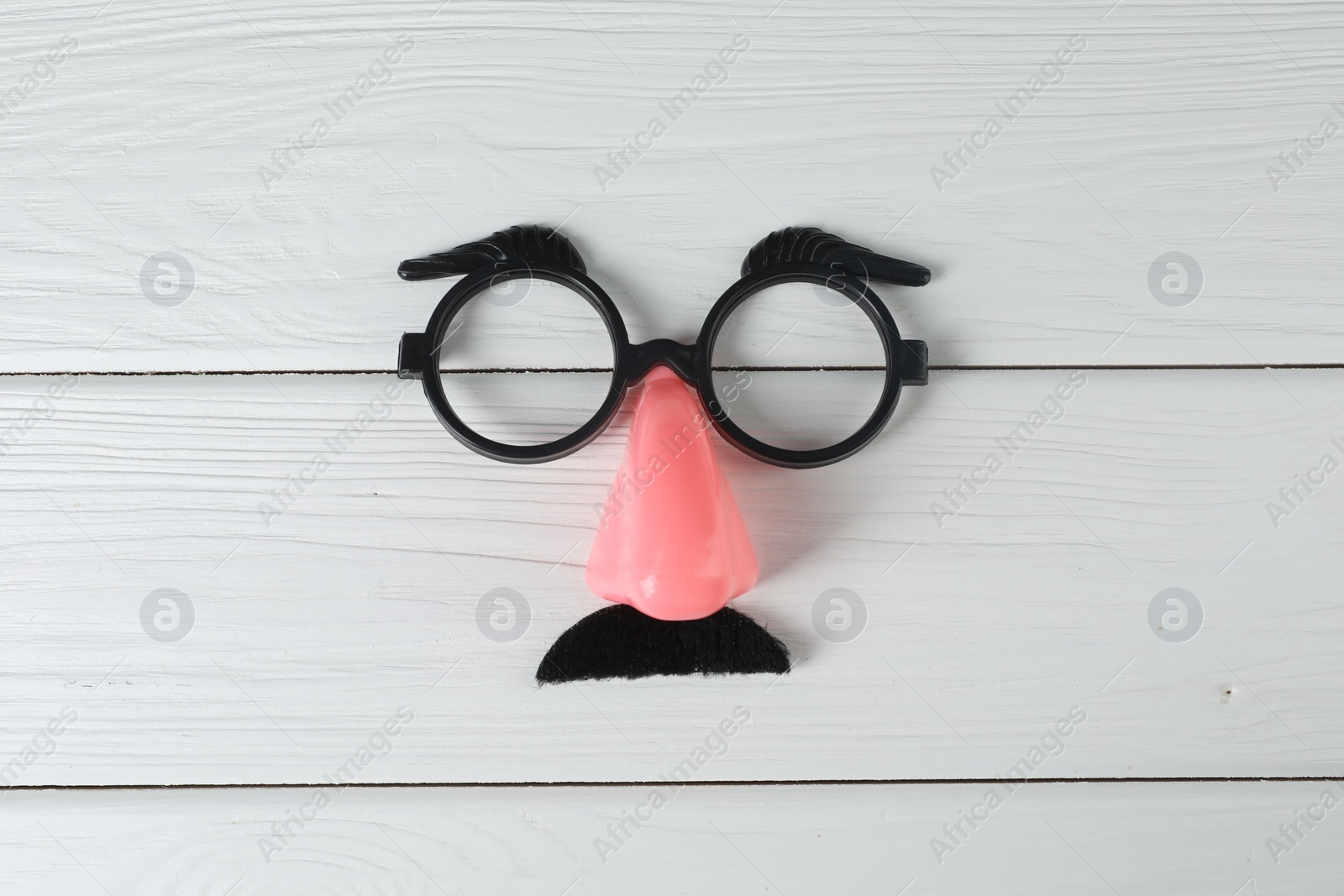 Photo of Funny mask with fake mustache, nose and glasses on white wooden background, top view