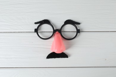 Funny mask with fake mustache, nose and glasses on white wooden background, top view