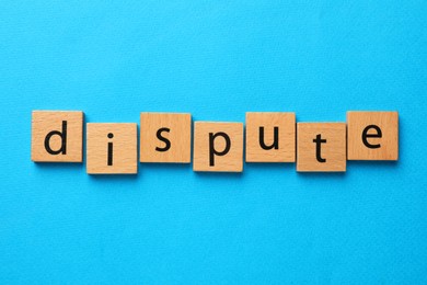 Photo of Word Dispute made with wooden cubes on light blue background, top view