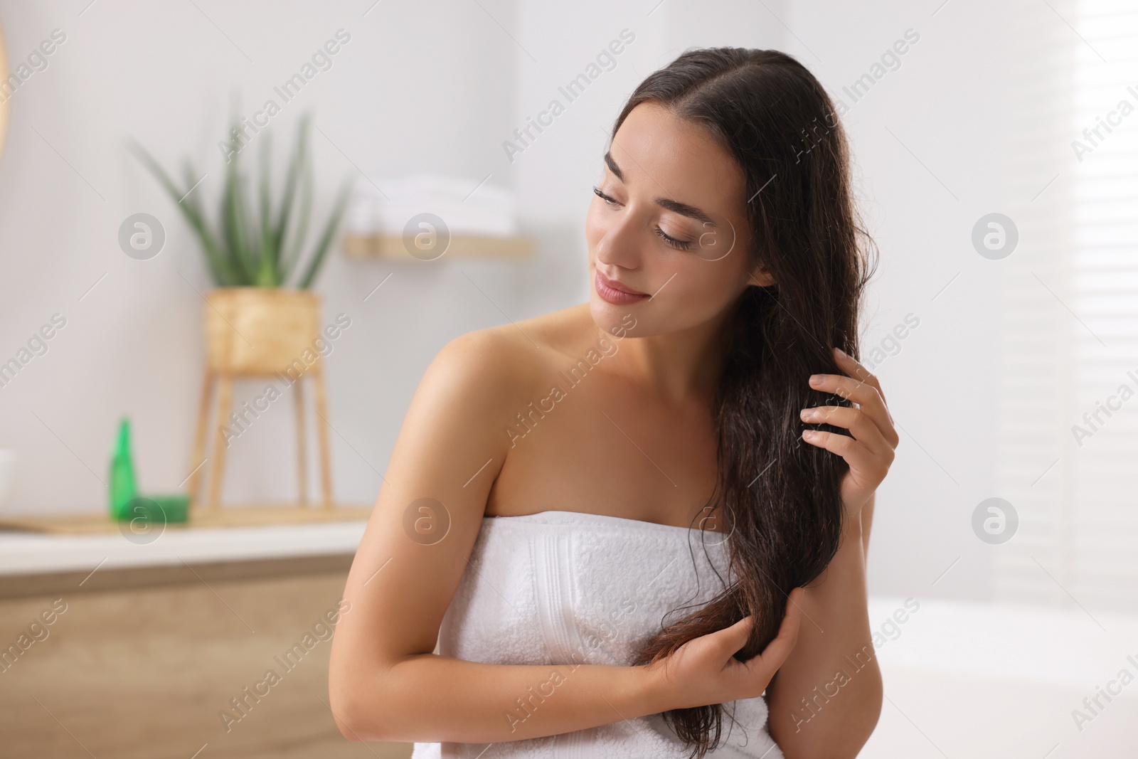 Photo of Young woman applying aloe hair mask in bathroom