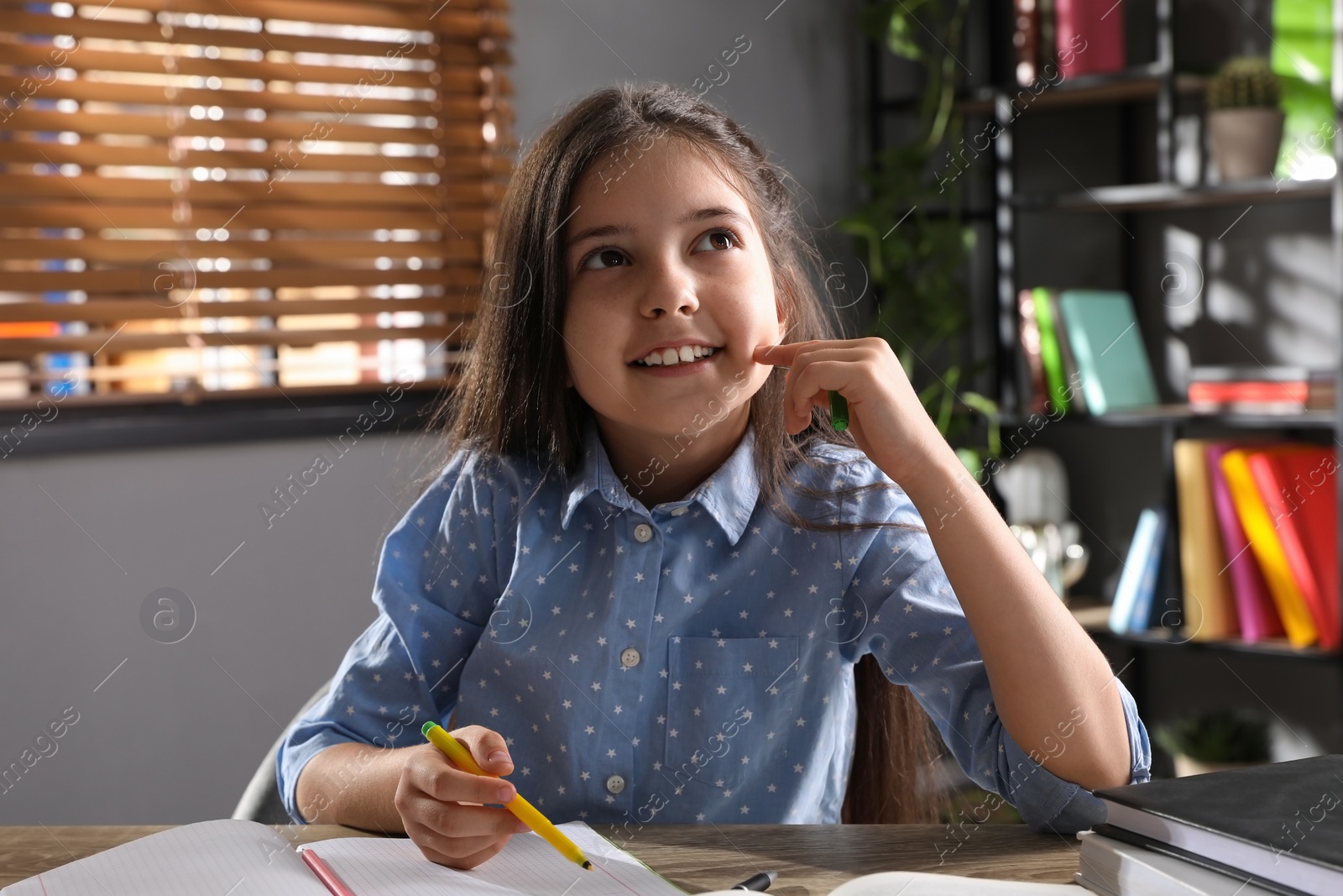 Photo of Cute preteen girl doing homework at table