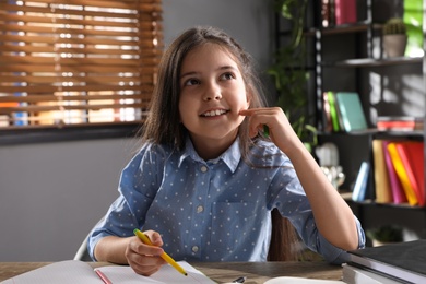 Cute preteen girl doing homework at table