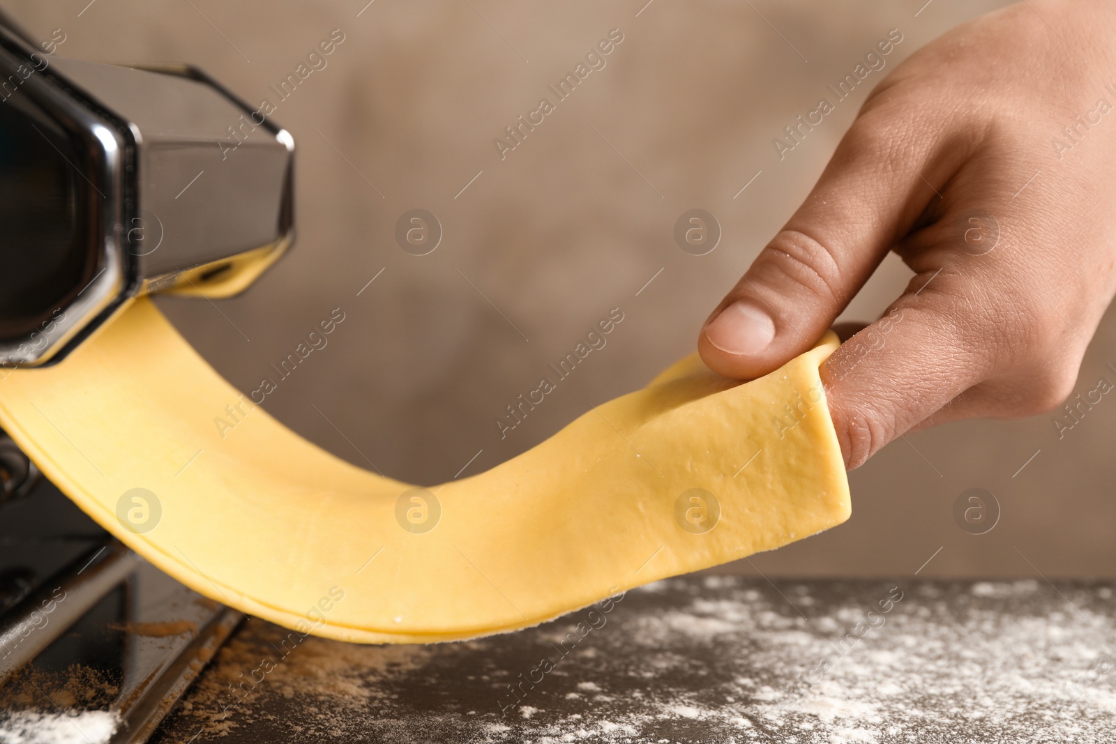 Photo of Woman preparing dough with pasta maker machine at table, closeup