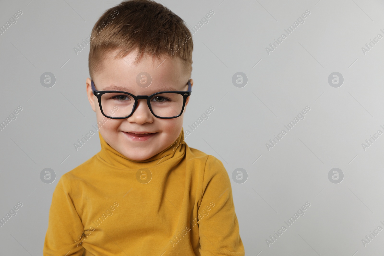 Photo of Cute little boy in glasses on light grey background. Space for text